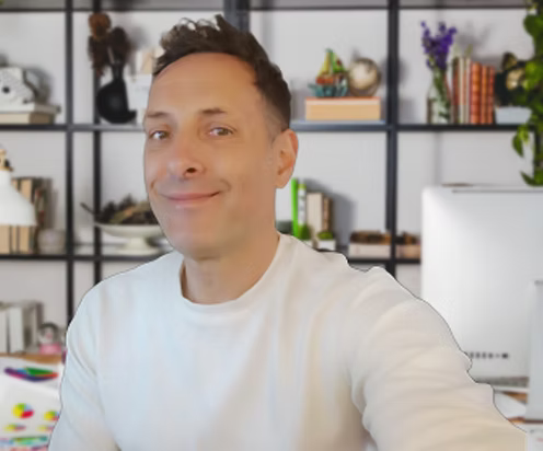Man in a white shirt sitting in front of a bookshelf with various items