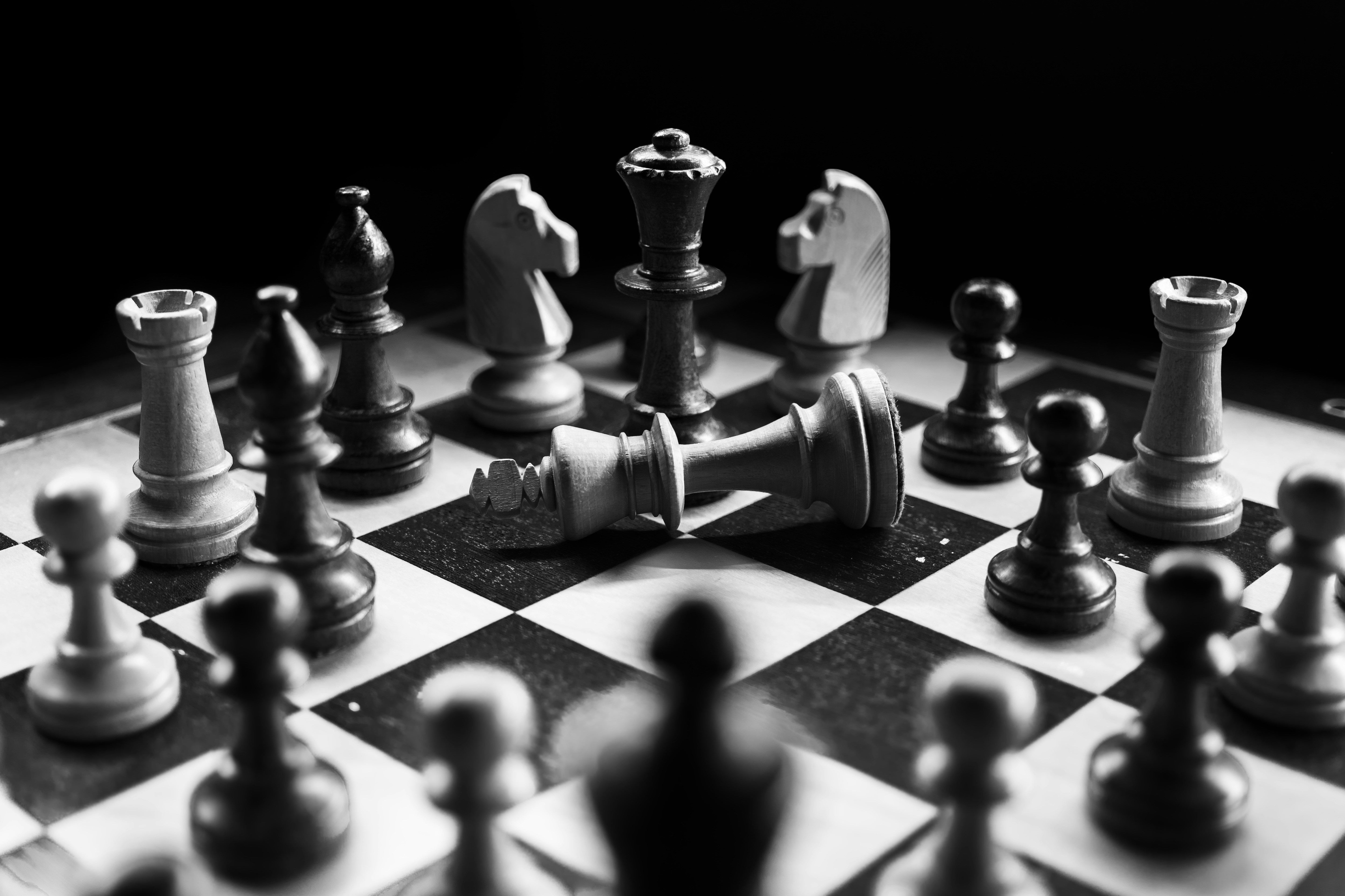 Black and white chess pieces on a board with a fallen king, representing strategic consulting, structured thinking, and expert problem-solving
